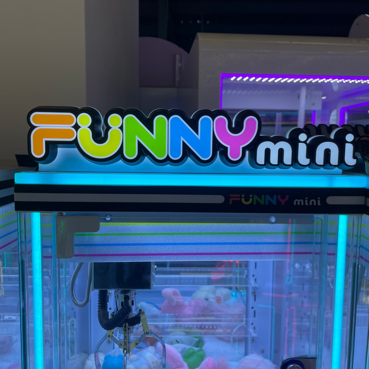 Personal mini claw machine interior view showing claw mechanism and game instruction stickers